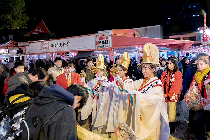 Shrine maiden ringing bell in festival of God Ebisu Toyonaka at Hattori Shrine