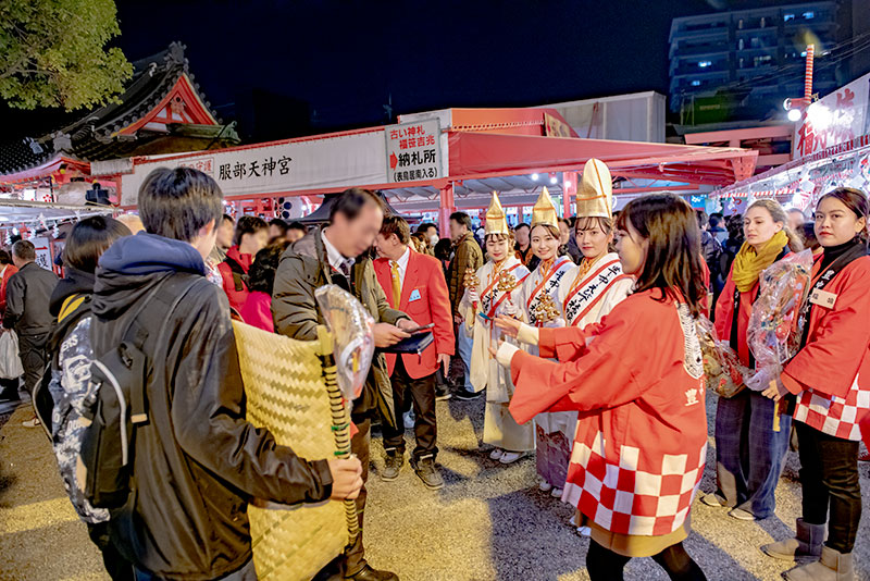 Shrine maiden ringing bell in festival of God Ebisu Toyonaka at Hattori Shrine